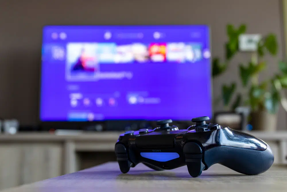 DLC de jeux vidéo : ce qu’il faut savoir manette-playstation-pose-devant-ecran
